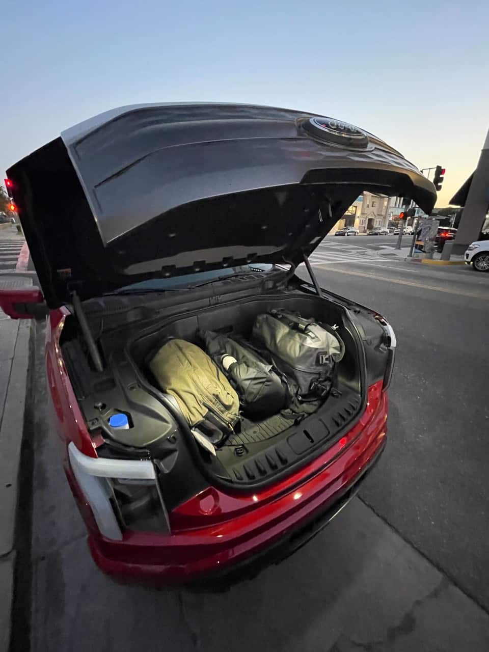 The frunk of a Ford F-150 Lightning shown packed with luggage and illuminated by an overhead light.